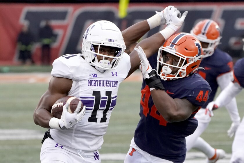Northwestern running back Andrew Clair (11) tries to stiff arm Illinois linebacker Tarique Barnes during the first half of an NCAA college football game Saturday, Nov. 27, 2021, in Champaign, Ill. (AP Photo/Charles Rex Arbogast)