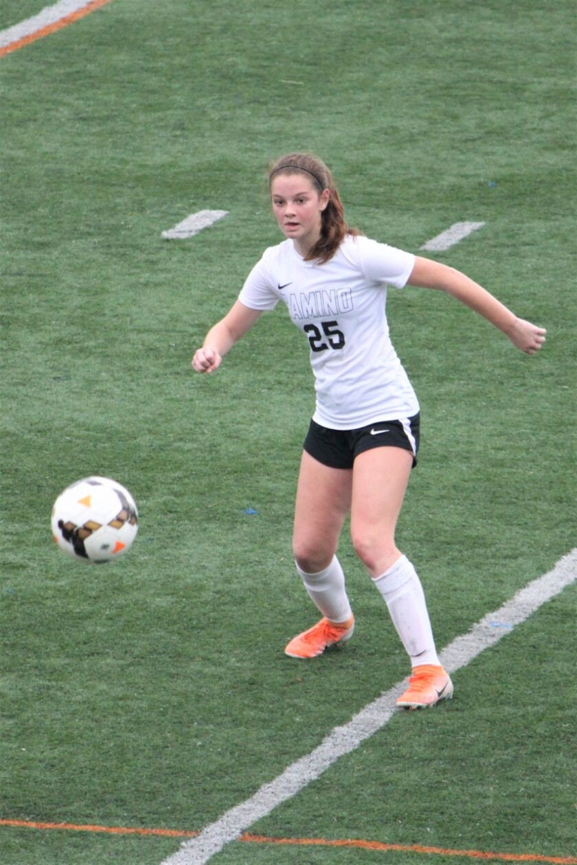 Erin Lee, in her high school soccer uniform, eyes the ball as it comes her way on the field.