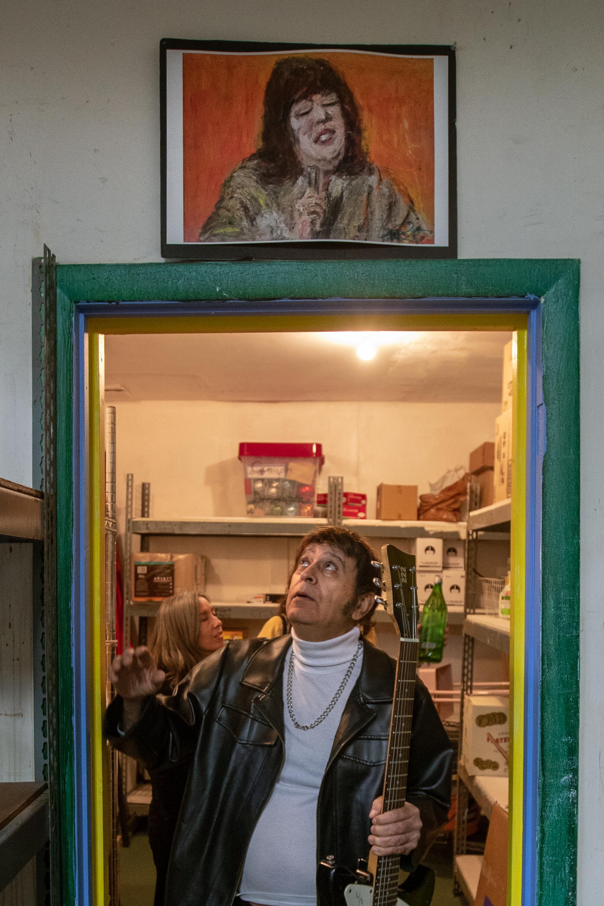 Tommy Bina walking through the threshold of a doorway, looking up at a painting on the wall above.