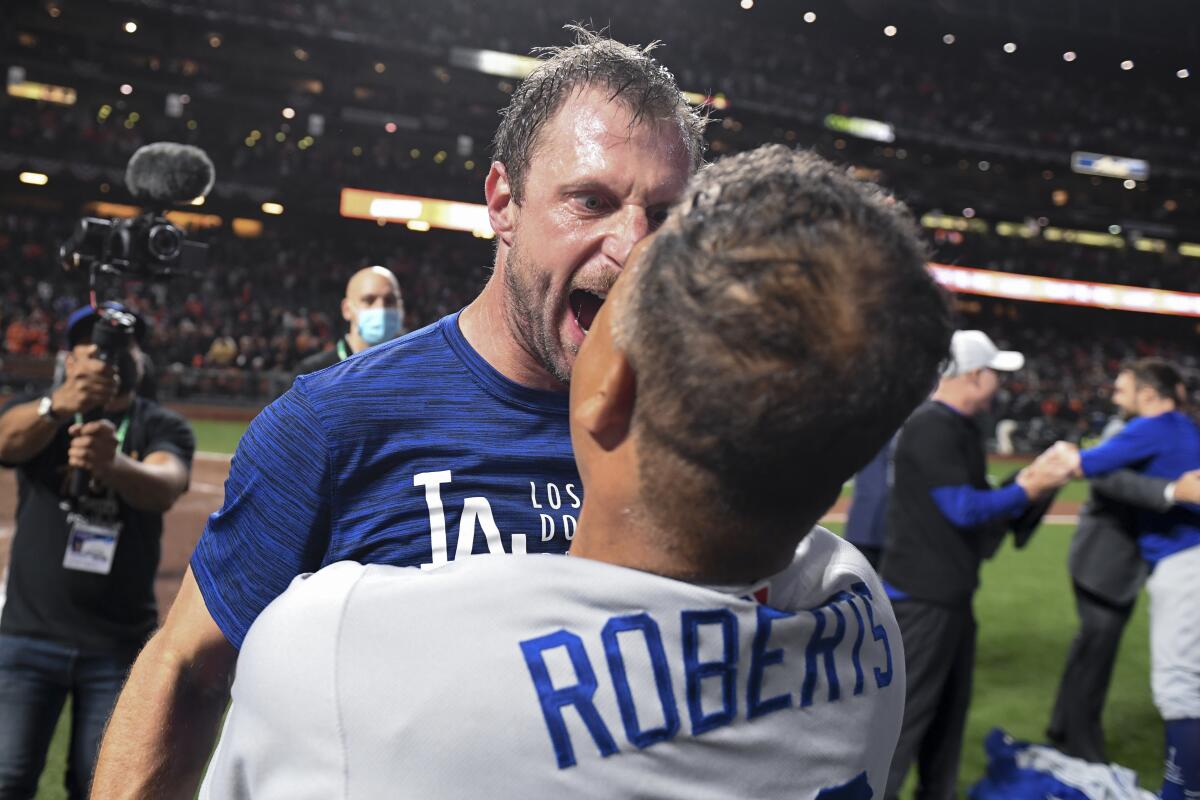 Dodgers pitcher Max Scherzer celebrates with manager Dave Roberts after defeating the San Francisco Giants.