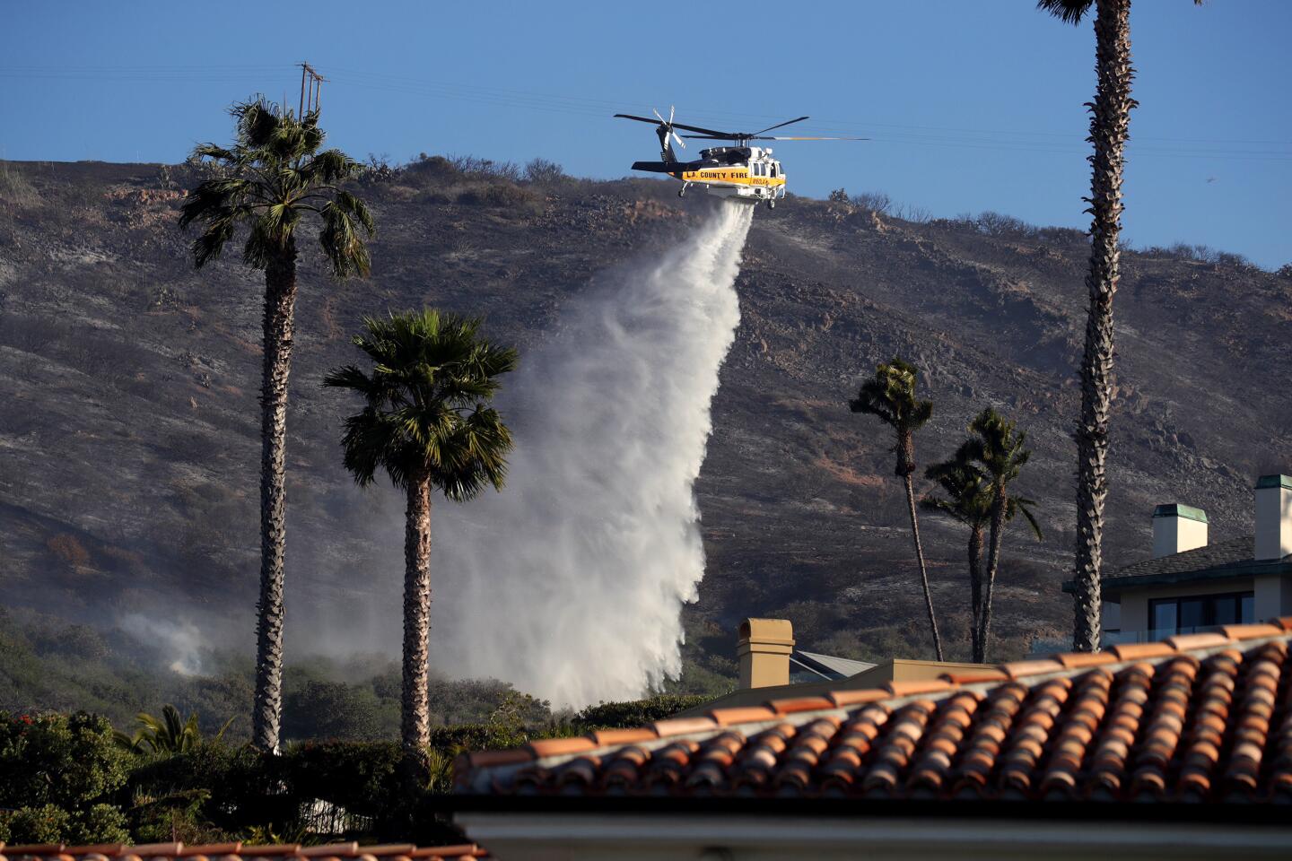 LAGUNA BEACH CA FEBRUARY 10, 2022 - A helicopter working the Emerald fire makes a water drop on the homes above Irvine Cove in Laguna Beach Thursday morning, February 10, 2022. (Irfan Khan / Los Angeles Times)