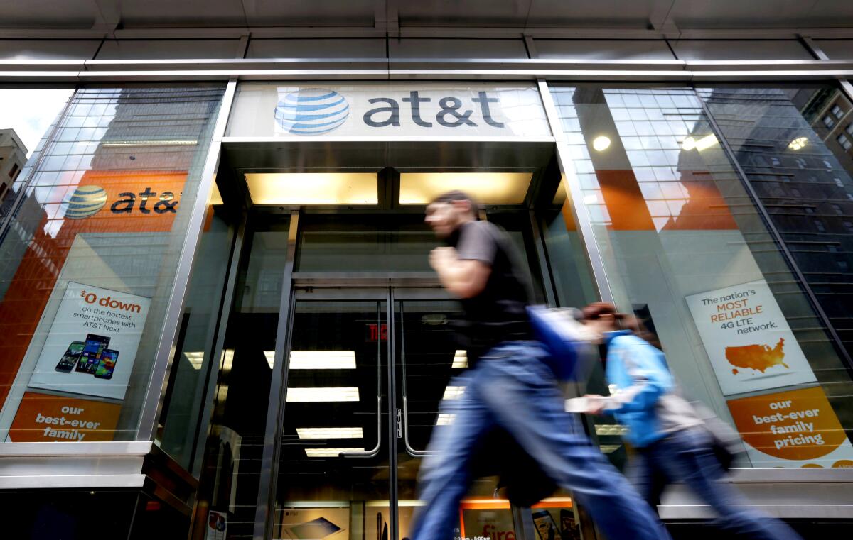People pass an AT&T store along New York's Madison Avenue.