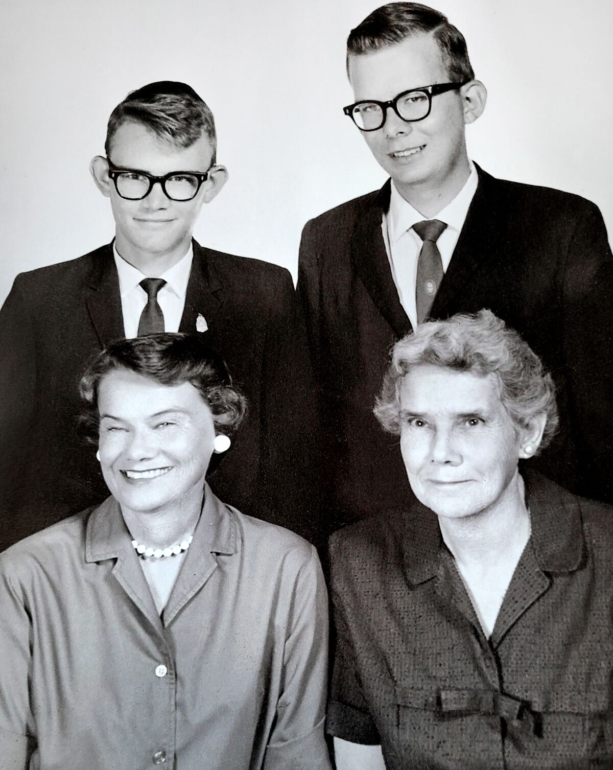 In their youth, Mike and Don Hunt, in horn-rimmed glasses and suits, take a formal photo with their mom and grandmother.
