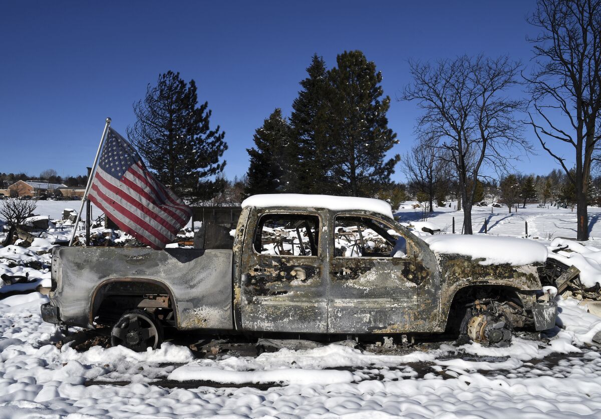 A burned truck in a destroyed neighborhood in Louisville, Colo., on Sunday, Jan. 2, 2022. Search teams looked for two missing people on Sunday in the snow-covered but still smoldering debris from a massive Colorado wildfire, while people who barely escaped the flames sorted through what was left after the blaze and investigators tried to determine its cause. (AP Photo/Thomas Peipert)