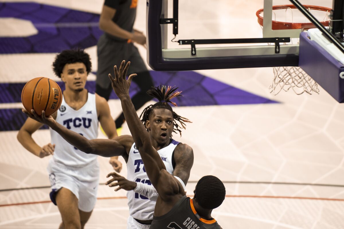 TCU guard Damion Baugh (10) attempts to get a shot off over Oklahoma State forward Moussa Cisse (33) in the first half of an NCAA college basketball game in Fort Worth, Texas, Tuesday, Feb. 8, 2022. (AP Photo/Emil Lippe)