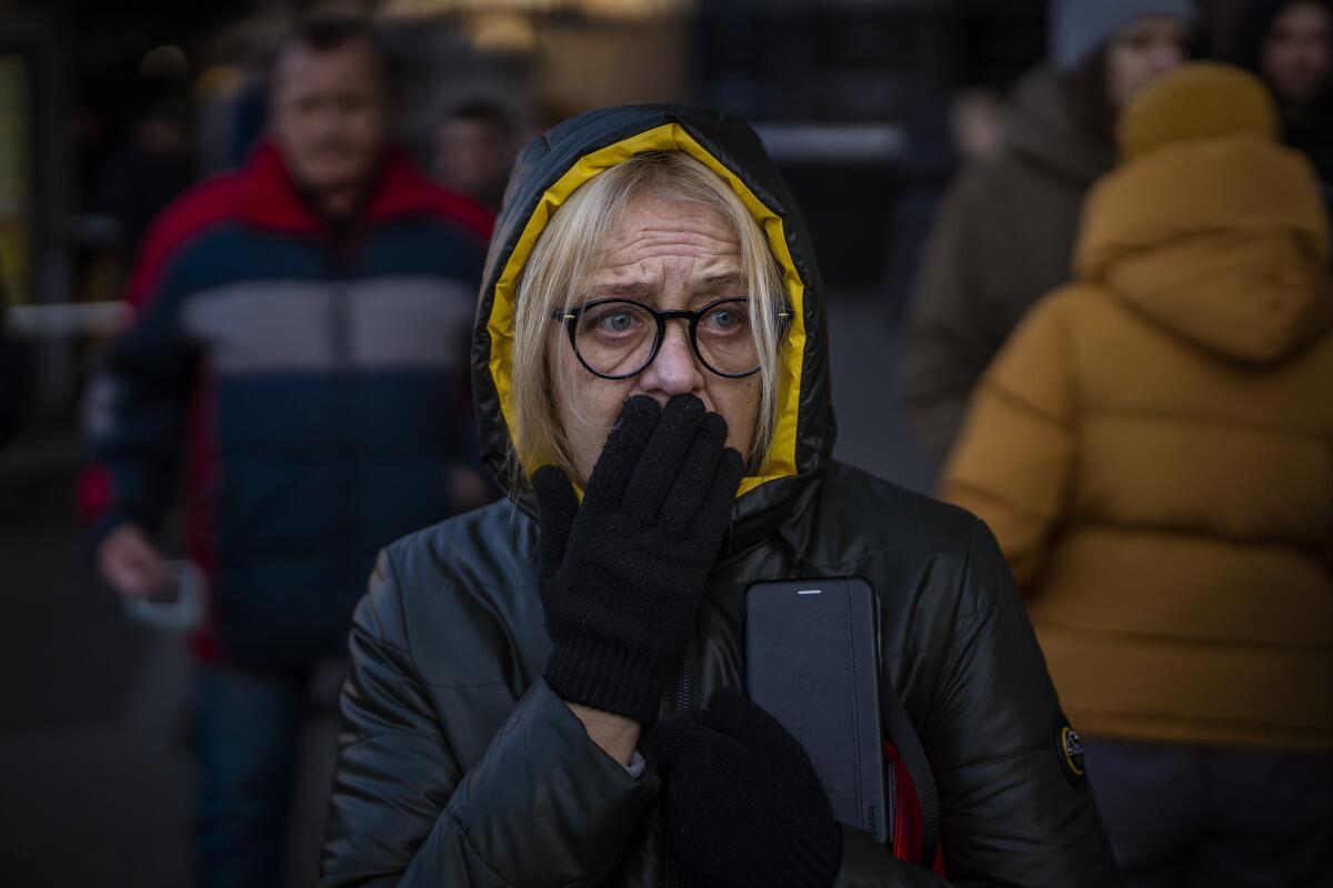 A woman in Kyiv looks frightened and holds a hand to her mouth in reaction to sirens signaling new attacks. 