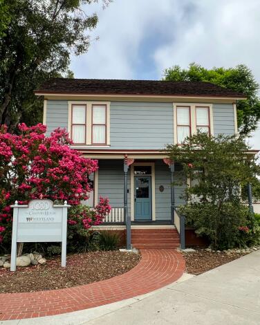 A blue, two-story house with a brick walkway in front of it.