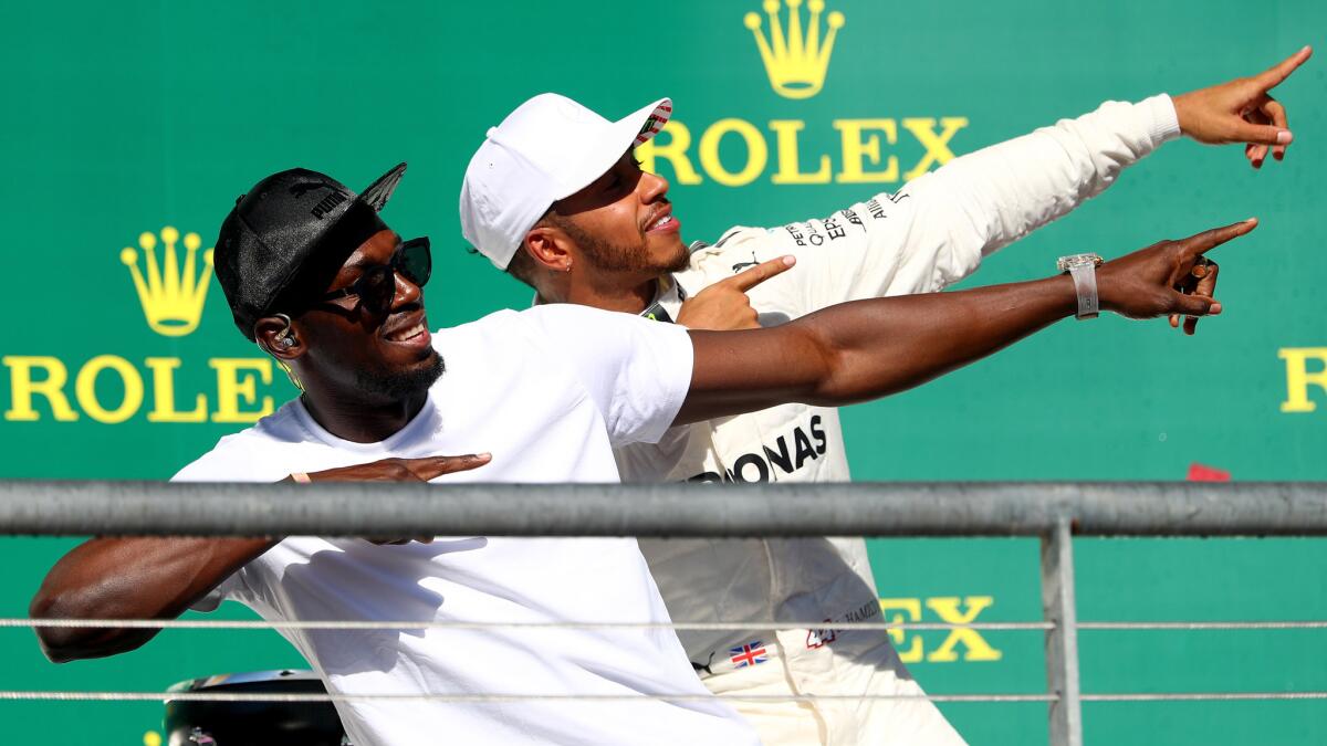 Olympic sprint champion Usain Bolt joins U.S. Grand Prix winner Lewis Hamilton on the podium Sunday to strike a familiar winning pose.