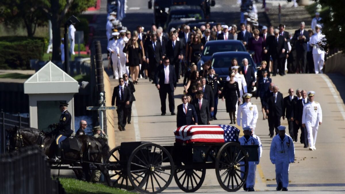Family members follow a horse-drawn caisson carrying the casket of Sen. John McCain to the Naval Academy cemetery in Annapolis, Md., on Sunday.