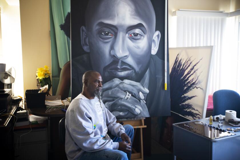 COMPTON, CA - OCTOBER 28: Portrait of Fulton Leroy Washington (who is known as Mr. Wash), sitting inside inside his aprtment / studio infront of his paintings on Wednesday, Oct. 28, 2020 in Compton, CA. While serving a life sentence in prison for a non-violent drug offense he says he didn't commit, Fulton Leroy Washington (who goes by Mr. Wash) took up painting, primarily making photo realistic portraits of other inmates - he made 50-75 works a year. One of his paintings, "Mondaine's Market," of his friend and fellow inmate John Mondaine, somehow got lost in the prison system. Mr. Wash is now free and lives/paints in Compton - but he never forgot the lost painting. When the Hammer Museum approached him about inclusion in this year's Made in L.A." biennial, Mr. Wash made an exact replica of the lost painting to be shown in the exhibition. And while he was doing so, he managed to track down Mondaine in Kansas City - and he was reunited with the lost work. The original will now hang alongside the replica in the Hammer biennial, which this engages with themes of dualities and reflections, so the two works have added resonance. (Francine Orr / Los Angeles Times)