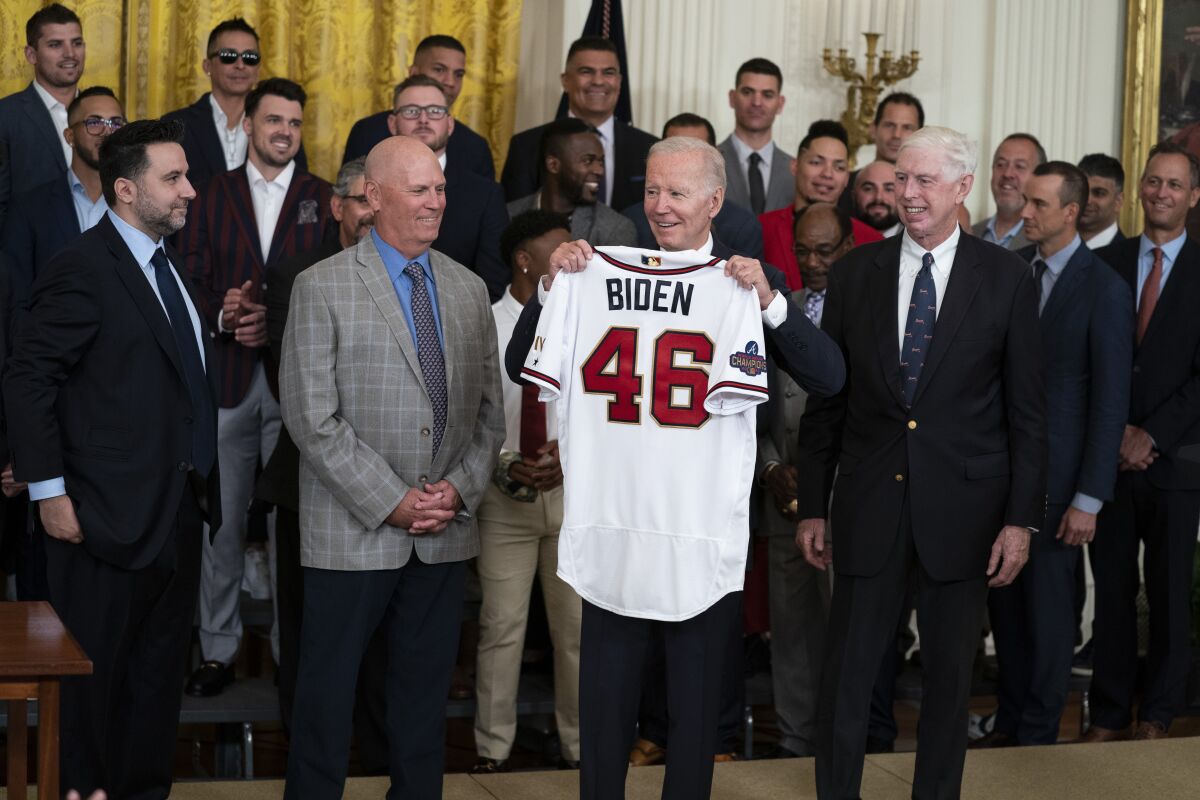El presidente Joe Biden alza una casaca durante un acto en la Casa Blanca