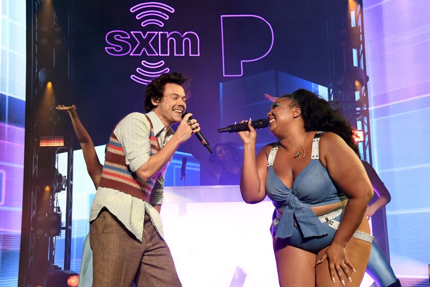 A man and a woman facing each other while singing into microphones on a stage