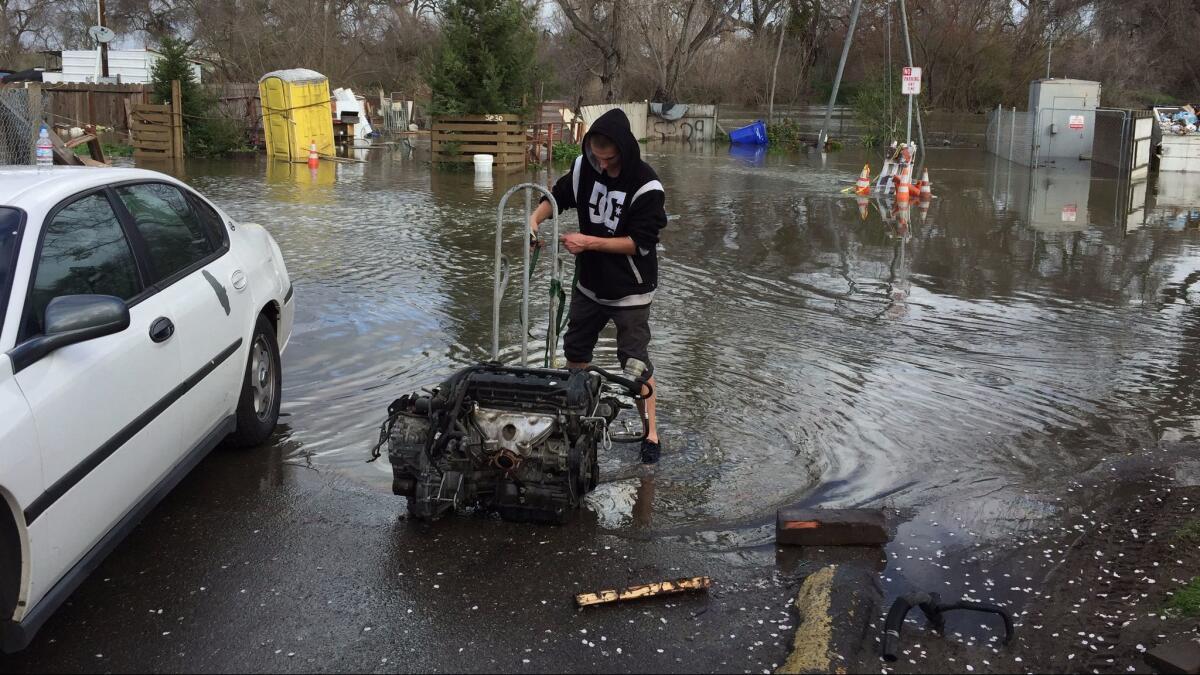 Dylan Douglas Hamlin, 21, straps up a car motor at Modesto's Driftwood Mobile Home Park on Tuesday morning. He's leaving the park because of the Tuolumne River's flooding.