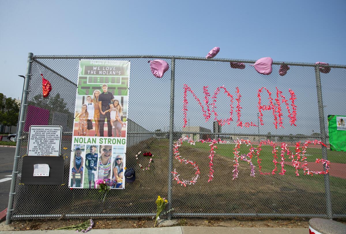 Posters and signs line a fence at Costa Mesa High School on Monday for football coach Jimmy Nolan's family.