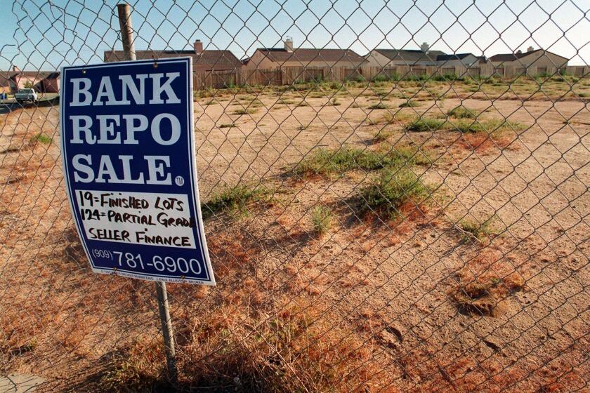 A bank repossession sign stands in front of an unoccupied housing division in April 1998, in Adelanto. The city is currently $2.6 million in debt.