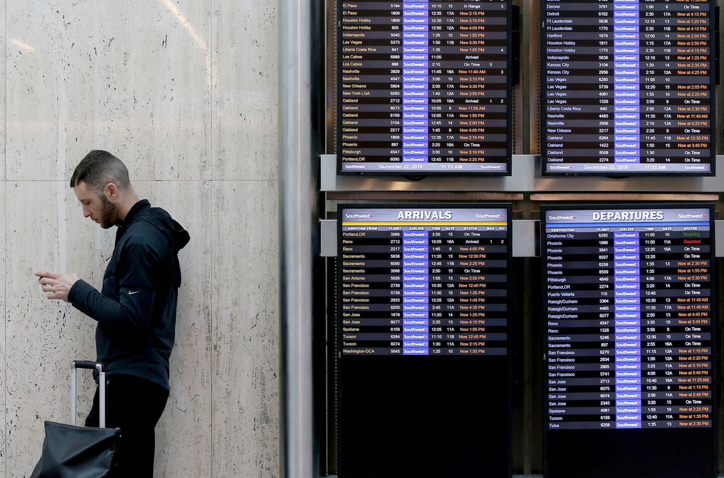 A traveler pauses beside a Southwest Airlines sign board showing dozens of flights to be delayed at LAX on Thursday.