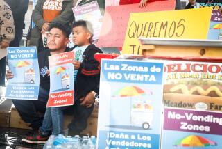 HOLLYWOOD-CA - DECEMBER 8, 2022: Jorge Cruz, left, and his son Luis, 5, gather with street vendors and supporters on Hollywood's Walk of Fame to demonstrate against an LA city ordinance created of eight citywide no vending zones, on Thursday, December 8, 2022. Cruz and his wife sell fruit in Santa Monica and say they are often harassed by police. (Christina House / Los Angeles Times)