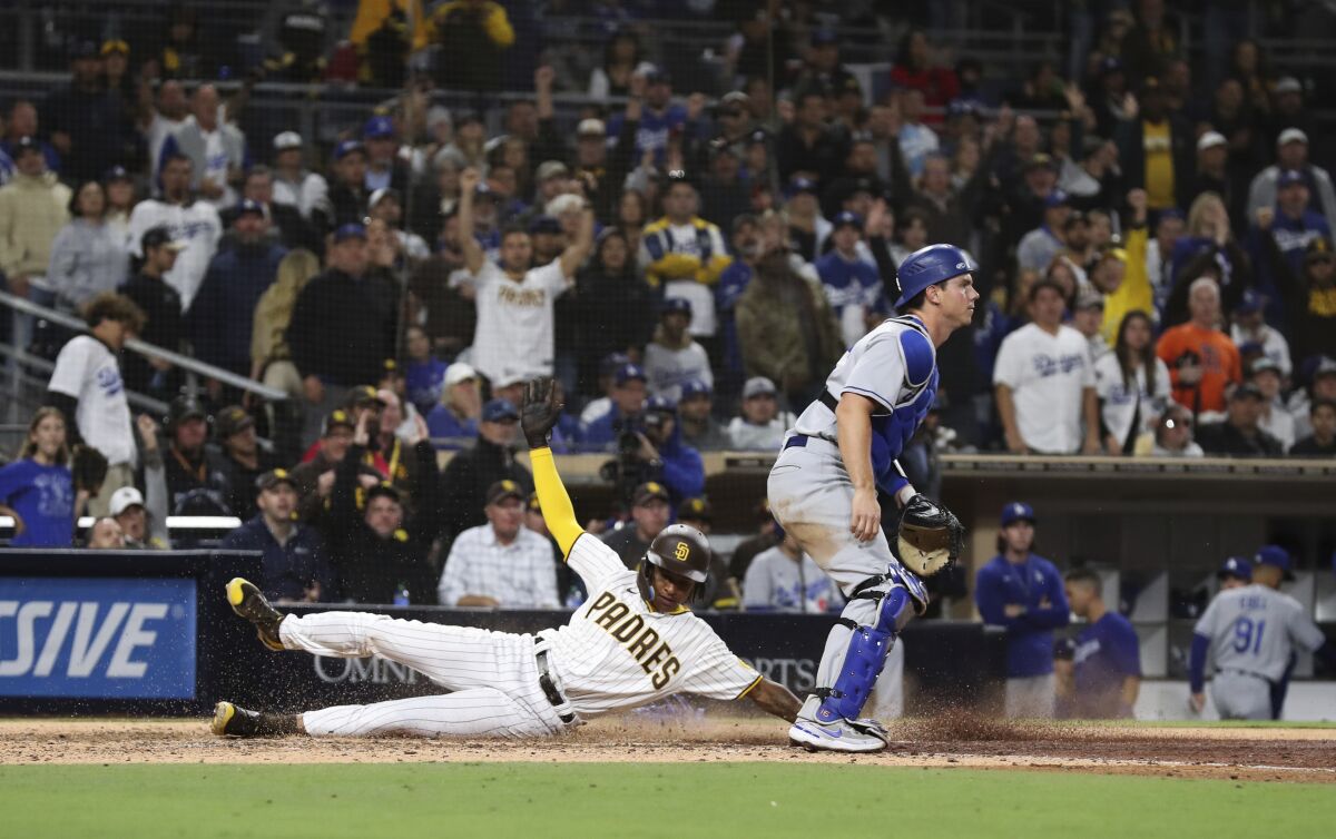 The Padres' C.J. Abrams scores the winning run on Austin Nola's sacrifice fly. Dodgers catcher Will Smith is at right.