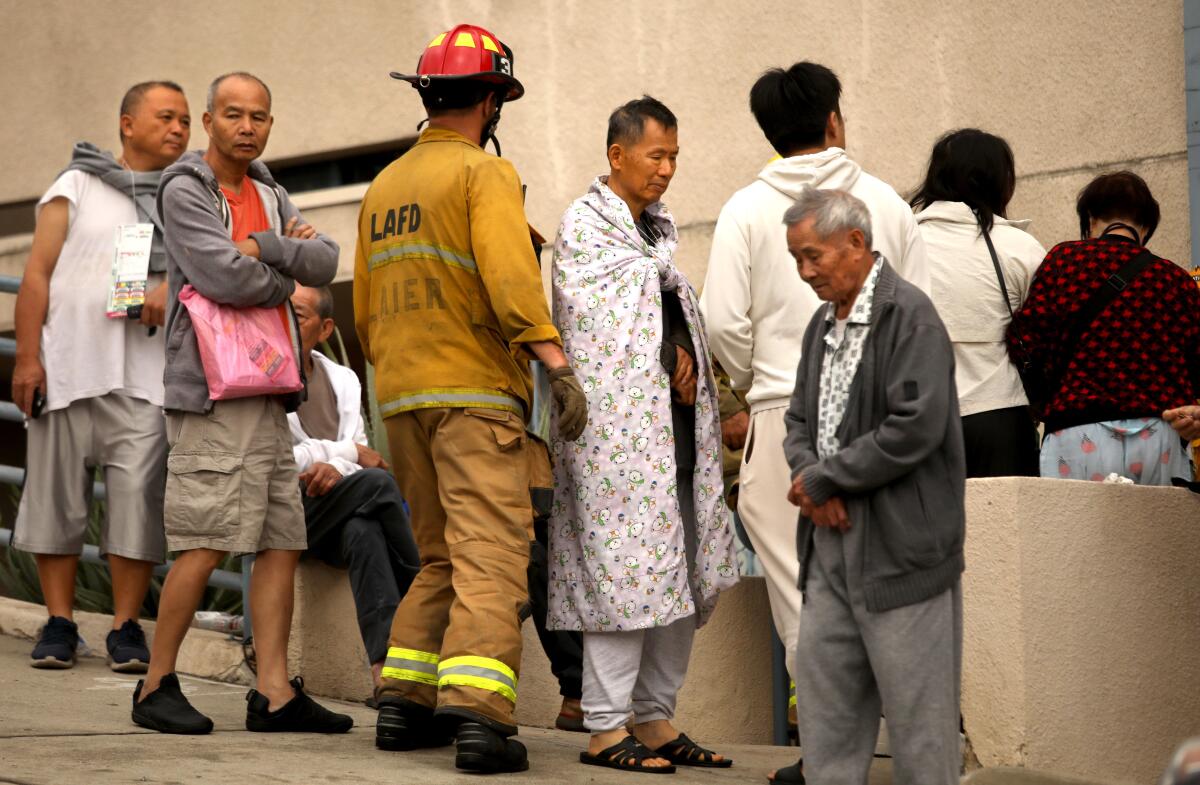 Residents stand outside their fire damaged apartment along 800 N. Bunker Hill Ave. in Chinatown.