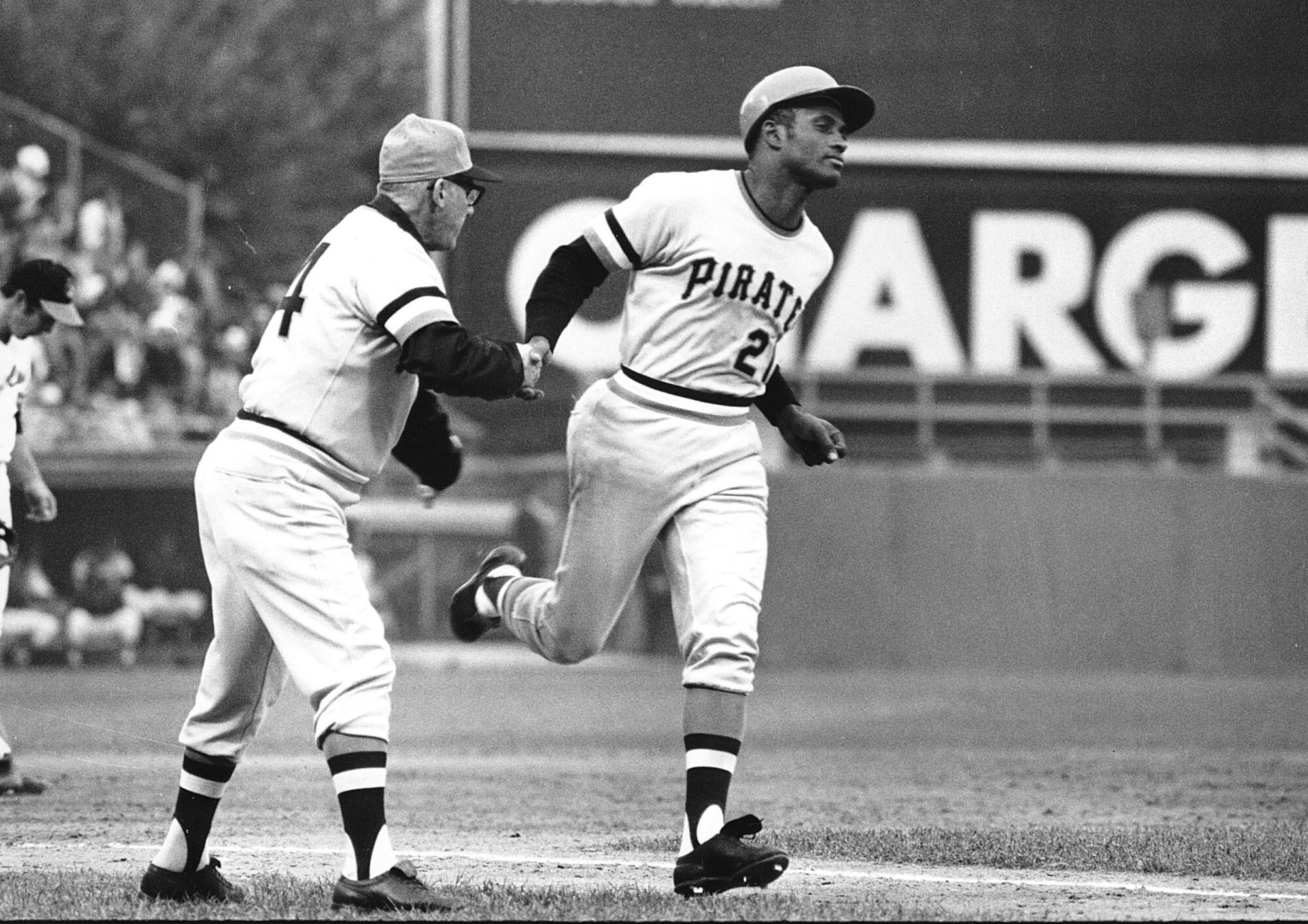 Roberto Clemente gets congratulations from third base coach Frank Oceak 