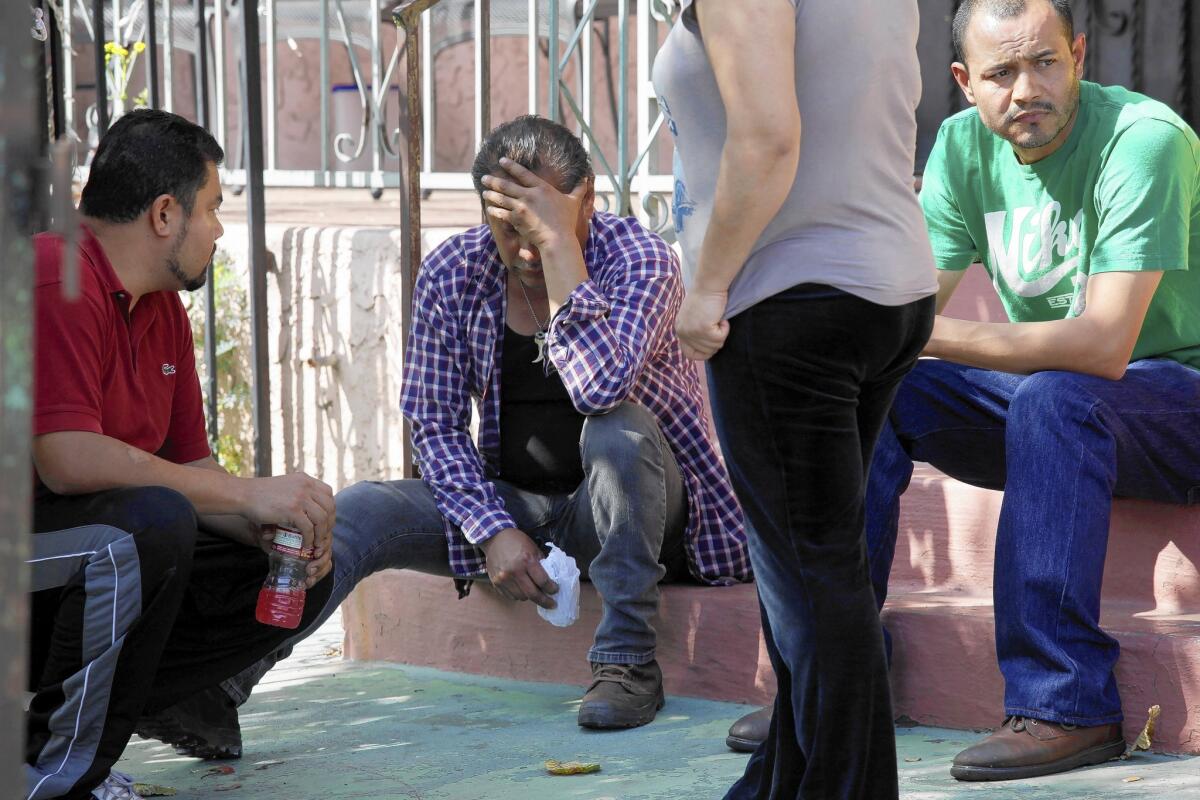 The father of a 2-year-old boy who died in the fire grieves outside the South L.A. home.