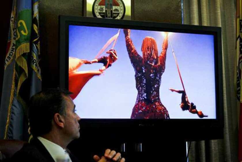 Developer Rick Caruso, a Coliseum commissioner, watches images of a rave at a meeting of the Coliseum Commission.