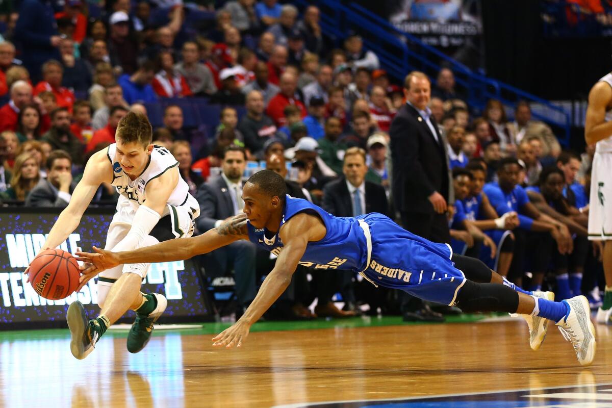 Middle Tennessee's Jaqawn Raymond, right, dives for the ball against Michigan State's Matt McQuaid.