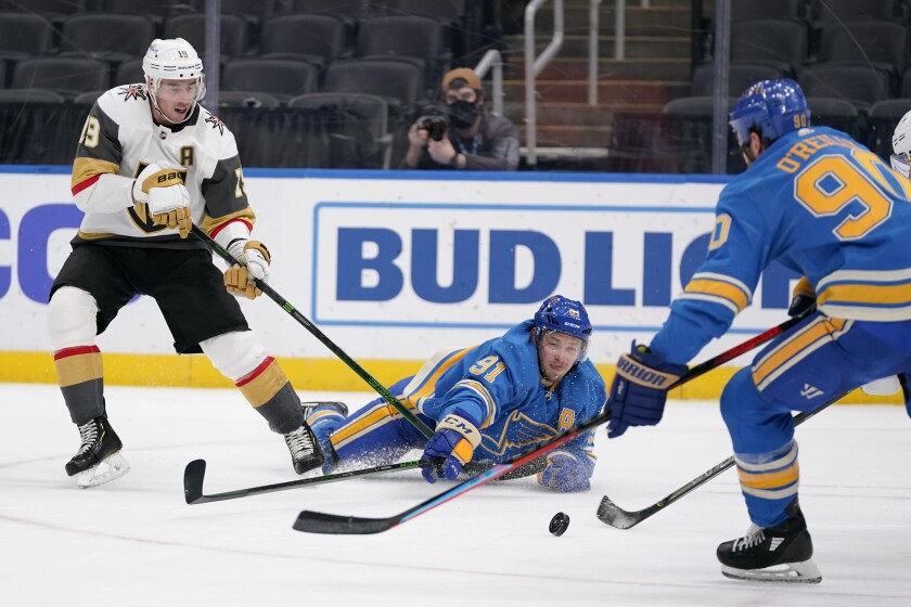 Vegas Golden Knights' Reilly Smith (19) watches as St. Louis Blues' Vladimir Tarasenko (91) and Ryan O'Reilly, right, reach for a loose puck during the second period of an NHL hockey game Saturday, March 13, 2021, in St. Louis. (AP Photo/Jeff Roberson)