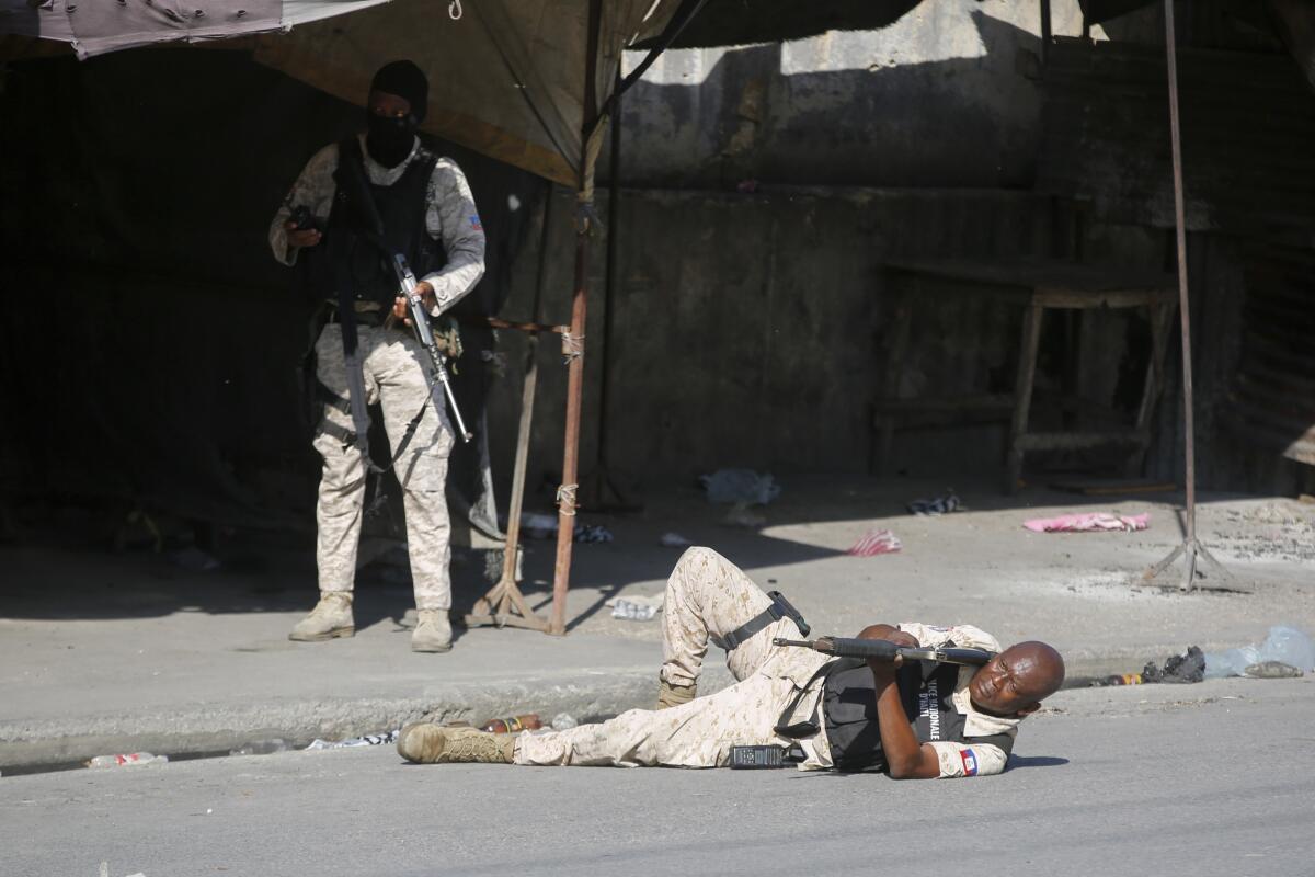 A police officer aims during clashes with gang members in Port-au-Prince, Haiti.