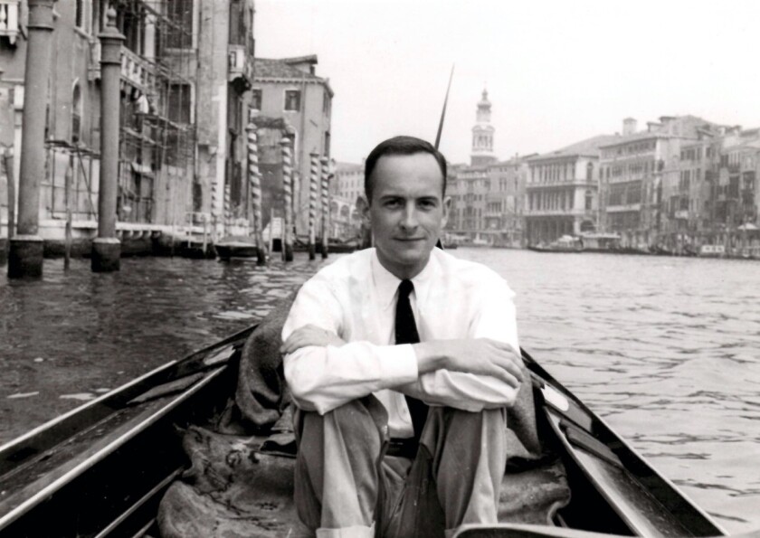 Un homme portant une chemise et une cravate est assis dans un bateau sur le Grand Canal de Venise