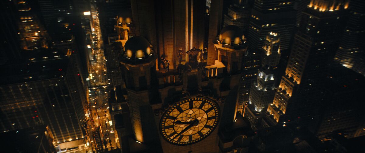 Une vue aérienne de Gotham City la nuit avec Batman visible sur une tour de l'horloge.  La ville n'est pas réelle ;  c'est un effet visuel.