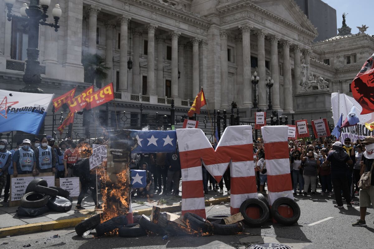 Oversized FMI letters, the Spanish acronym for International Monetary Fund, go up in flames during a protest outside Congress as legislators prepare to vote on a law to ratify the government's agreement with the IMF to refinance some $45 billion in debt, in Buenos Aires, Argentina. Thursday, March 10, 2022. (AP Photo/Rodrigo Abd)