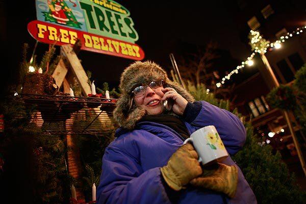 Patti Romp of Vermont sells Christmas trees 24 hours a day on Montague Street in Brooklyn Heights, N.Y., with help from her 14-year-old son, Tim. When business gets slow, she keeps warm with a cup of tea. Mother and son stay in a camper trailer in front of a supermarket adjacent to their stand.