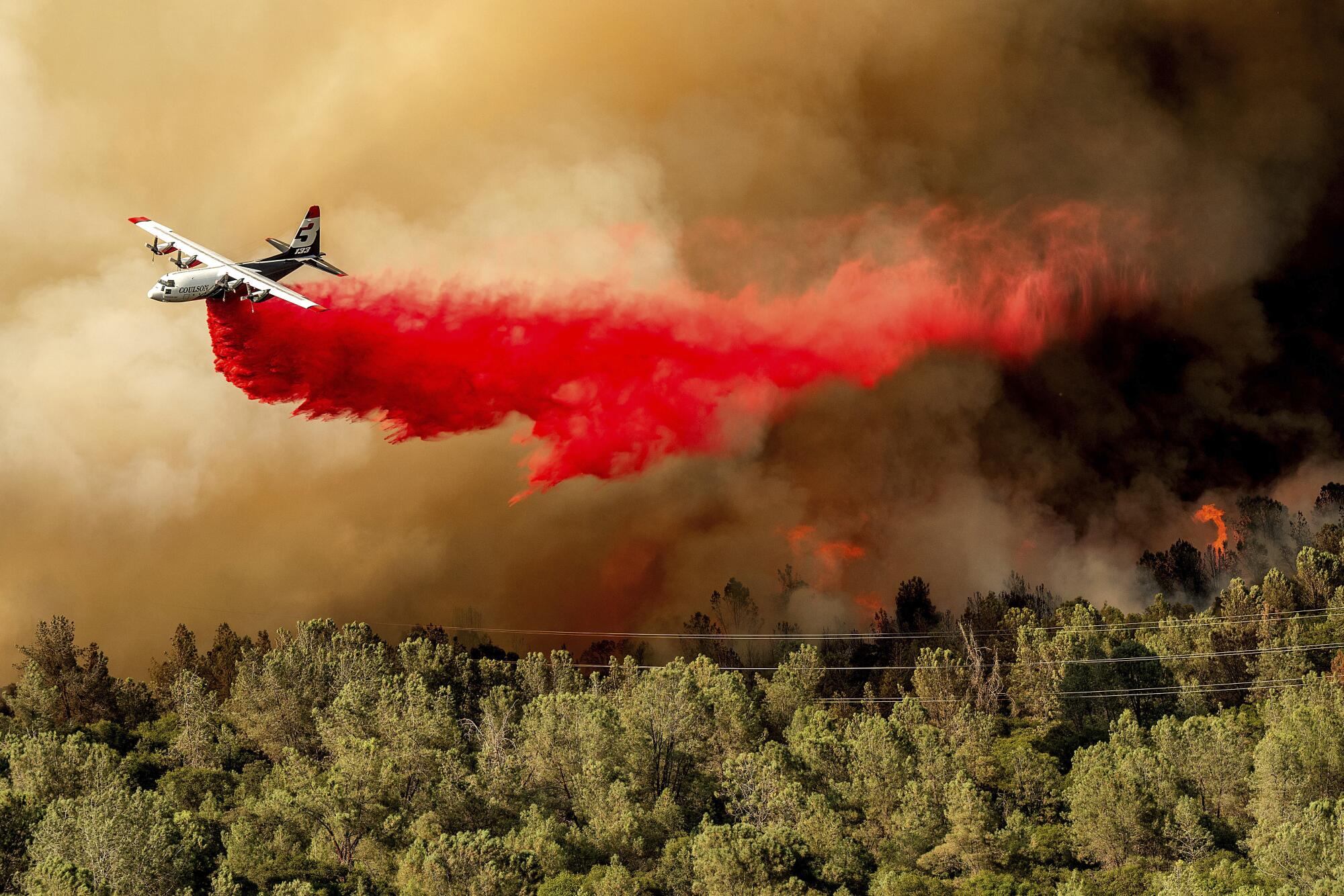 Un avión cisterna arroja retardante mientras lucha contra el incendio Thompson en Oroville.