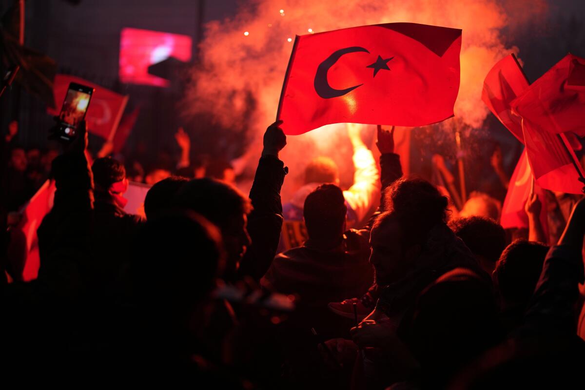 People wave Turkish flags.