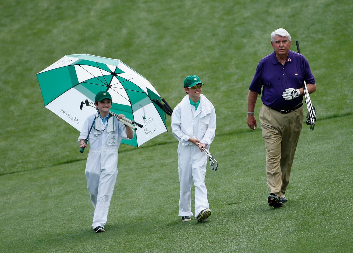 Charles Coody, who won the Masters in 1971, walks with two young caddies during the 2015 Par 3 Contest at August National Golf Club.