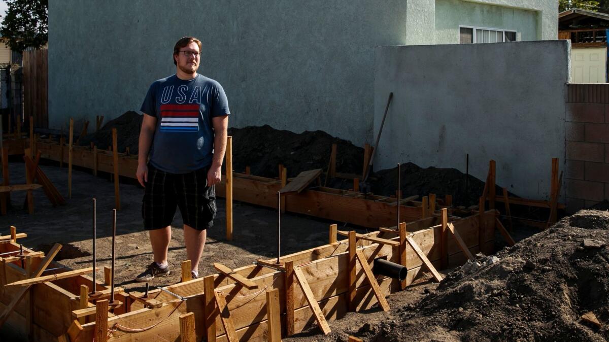 John Gregorchuk posa en medio de los cimientos de la construcción de una residencia que está construyendo en su patio trasero en Los Ángeles.