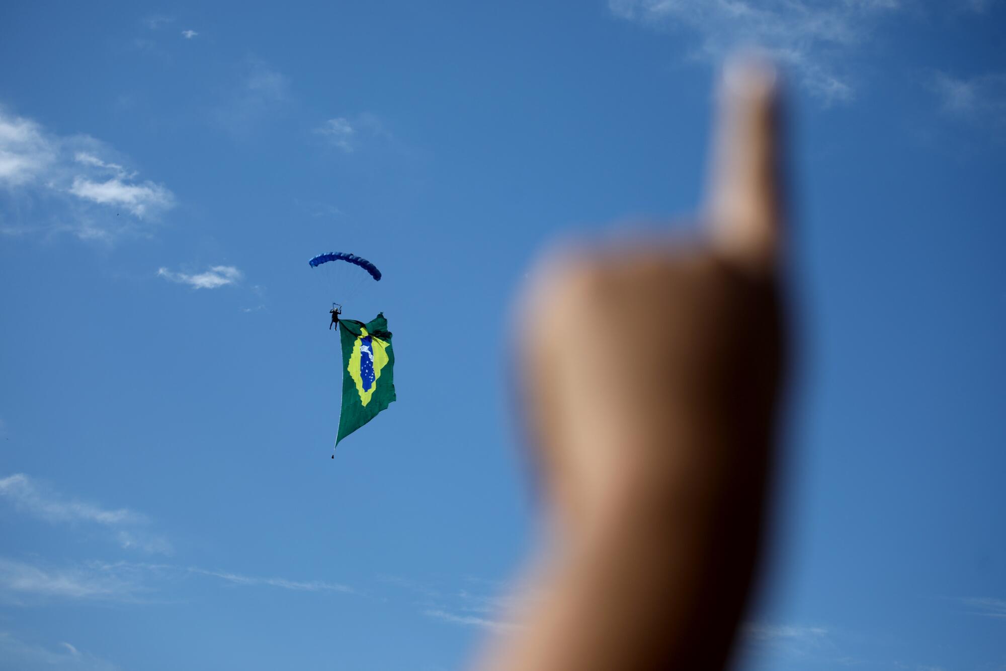 A finger points up as Brazilian miilitary paratroopers land.