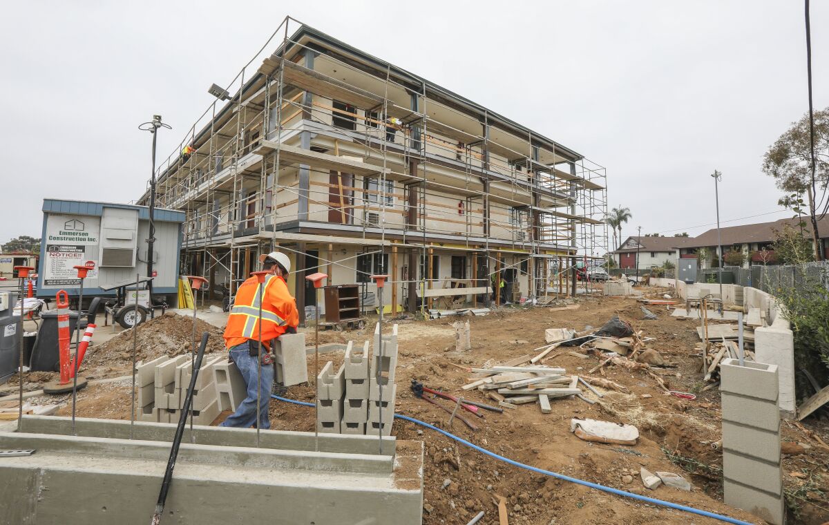 A worker carries construction materials at the Benson Place affordable housing project in San Diego in June.