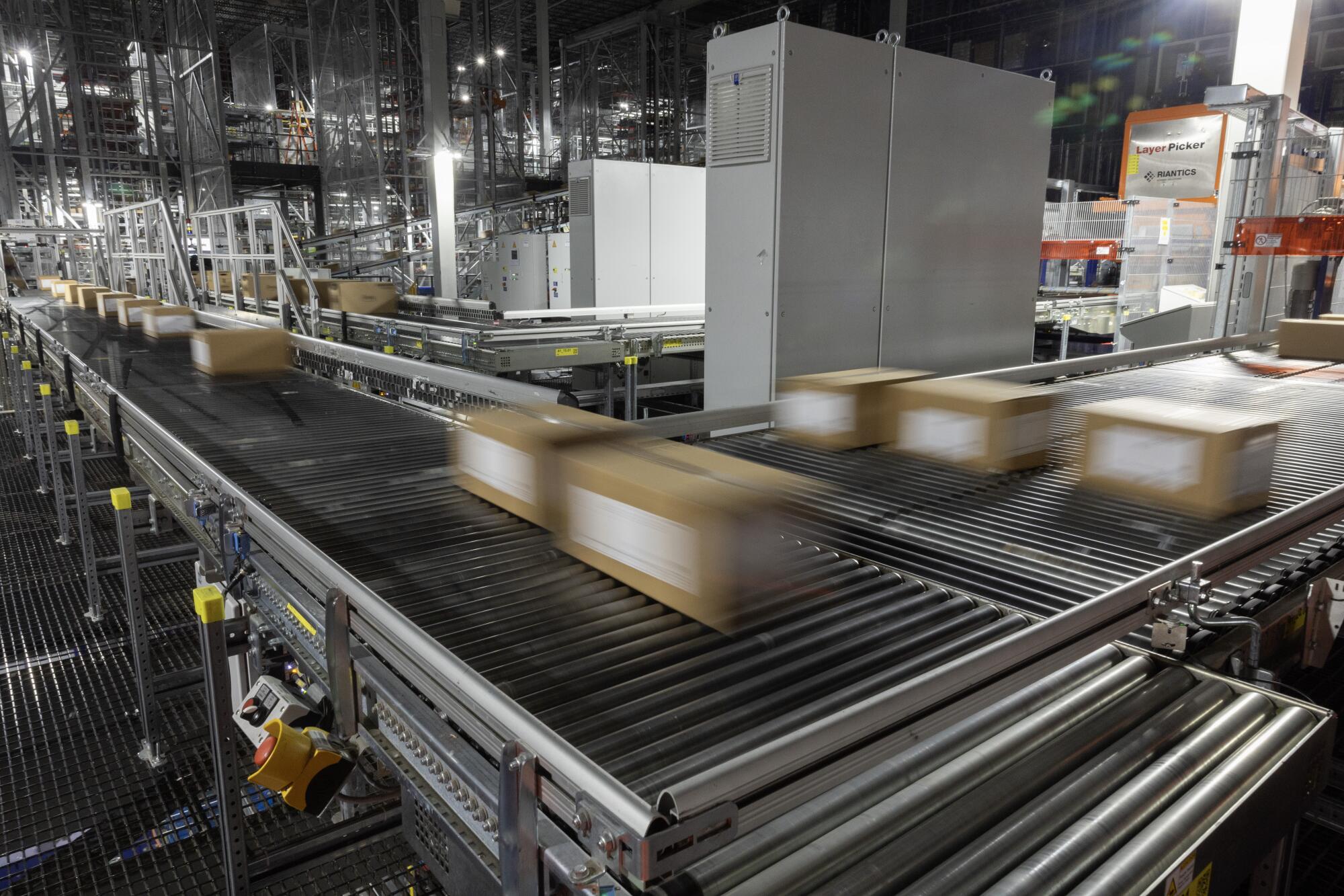 Products in boxes move along a conveyor belt in a warehouse. 
