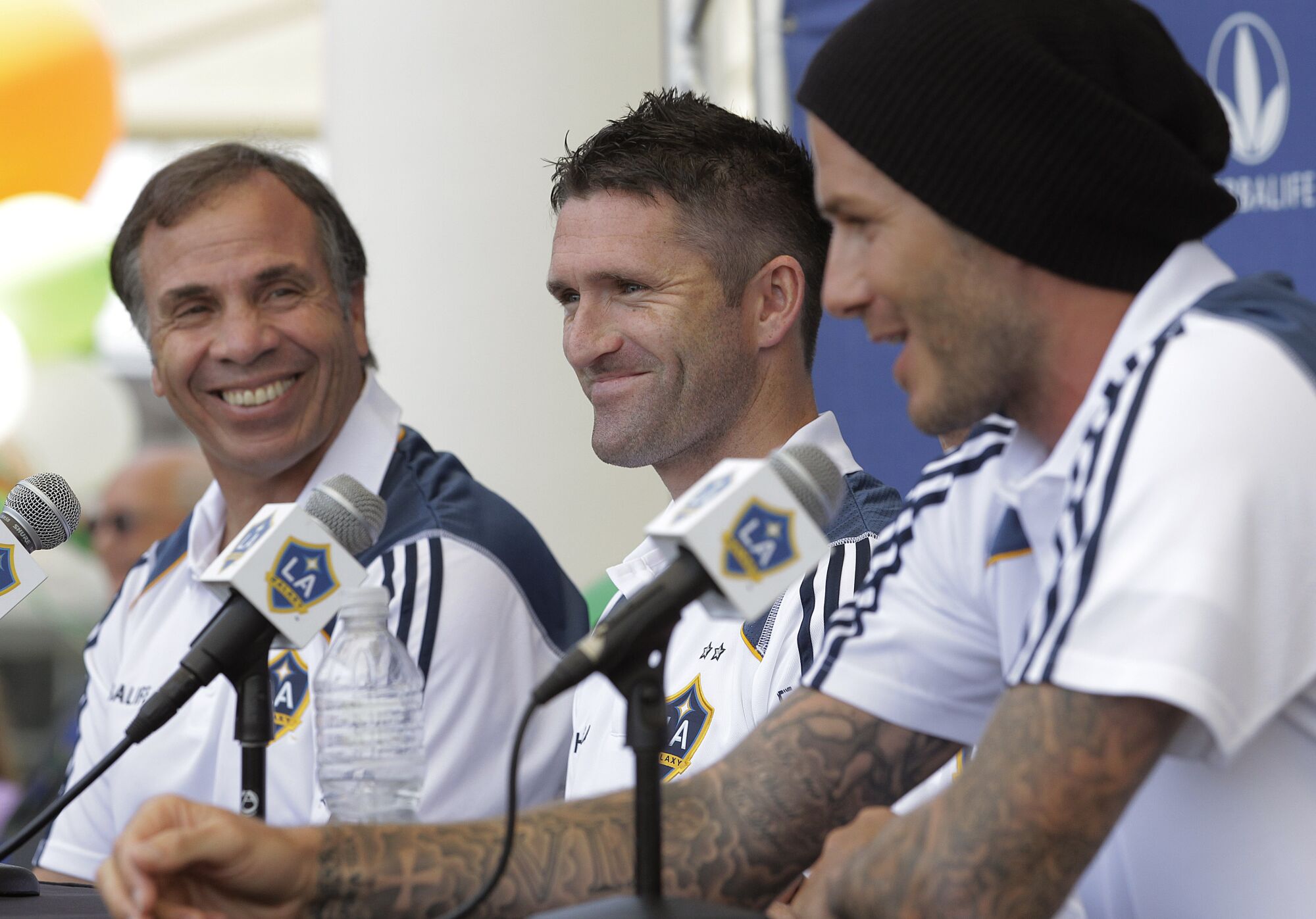 The Galaxy's Robbie Keane and coach Bruce Arena smile as they listen to David Beckham 