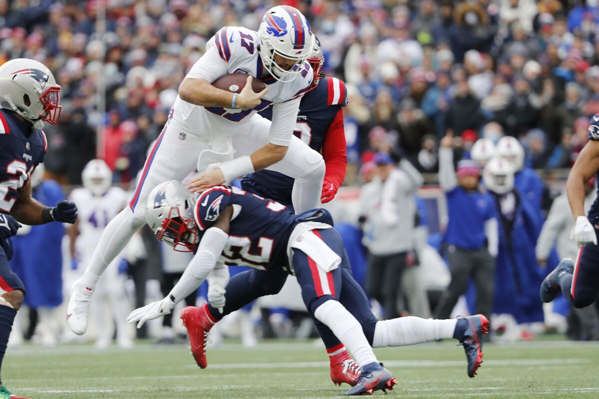 The Bills' Josh Allen leaps over the Patriots' Devin McCourty.