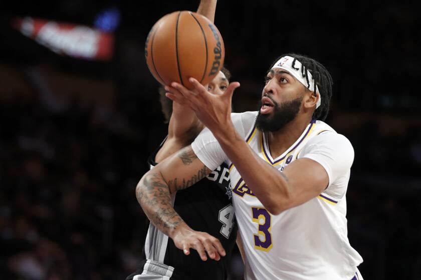 Los Angeles Lakers forward Anthony Davis, right, goes up against San Antonio Spurs guard Derrick White during the first half of an NBA basketball game Sunday, Nov. 14, 2021, in Los Angeles. (AP Photo/Alex Gallardo)