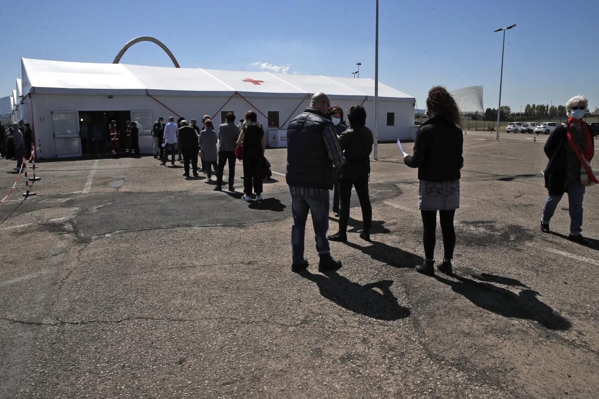 Un grupo de personas espera en fila en un centro de vacunación contra el COVID-19