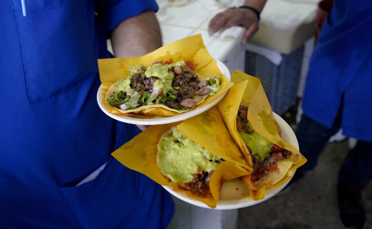 At the popular Taqueria Franc in Tijuana, Mexico on August 6, 2019, a waiter carries an assortment of carne asada and al pastor tacos to customers in the dining room.