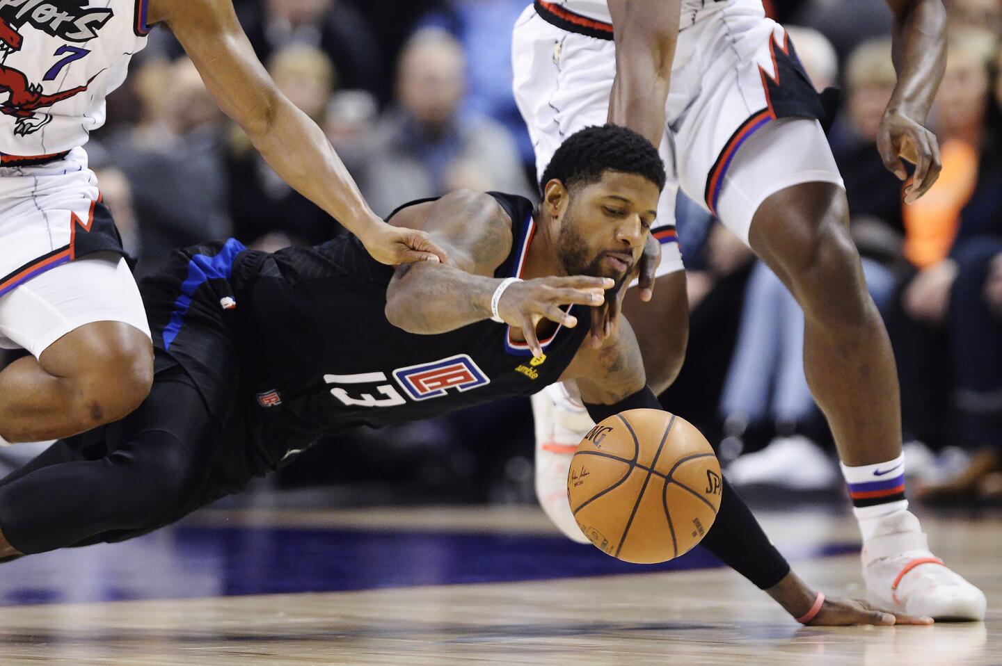 Clippers forward Paul George (13) dives for a loose ball during a game against the Raptors on Dec. 11.