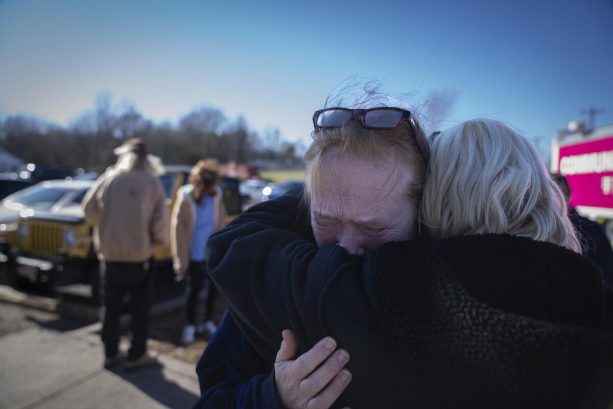 Tamara Yekinni hugs a friend outside a shelter in Wingo, Ky.,