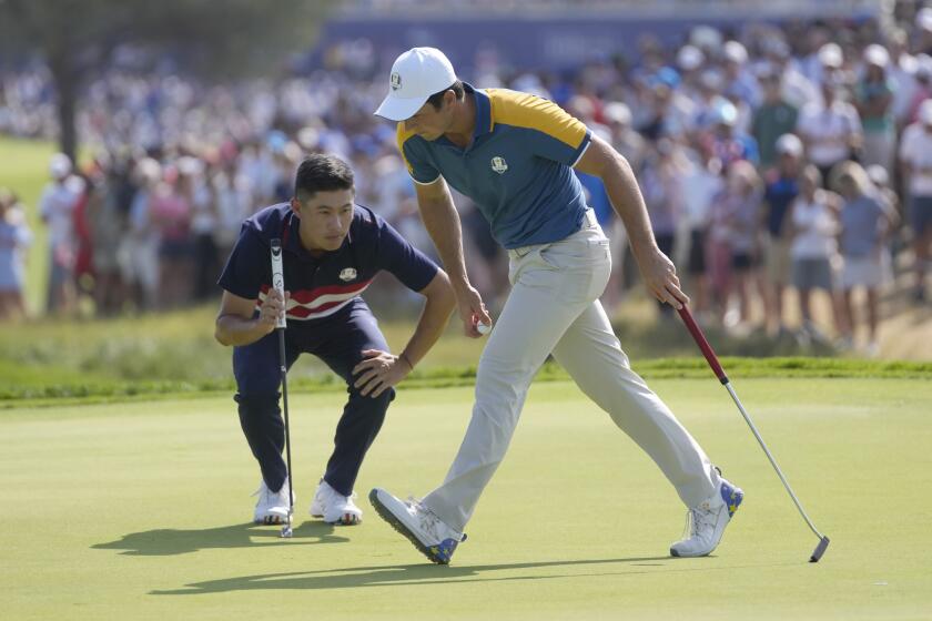 Europe's Viktor Hovland, walks on the 2nd green as United States' Colin Morikawa looks at his putt during their singles match at the Ryder Cup golf tournament at the Marco Simone Golf Club in Guidonia Montecelio, Italy, Sunday, Oct. 1, 2023. (AP Photo/Andrew Medichini)