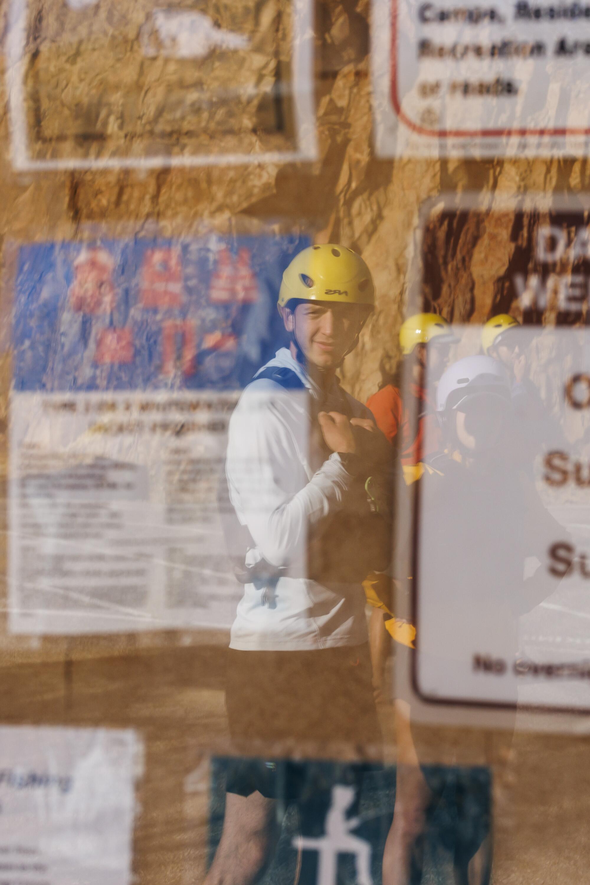 A man wearing a helmet reflected in the window of the display board