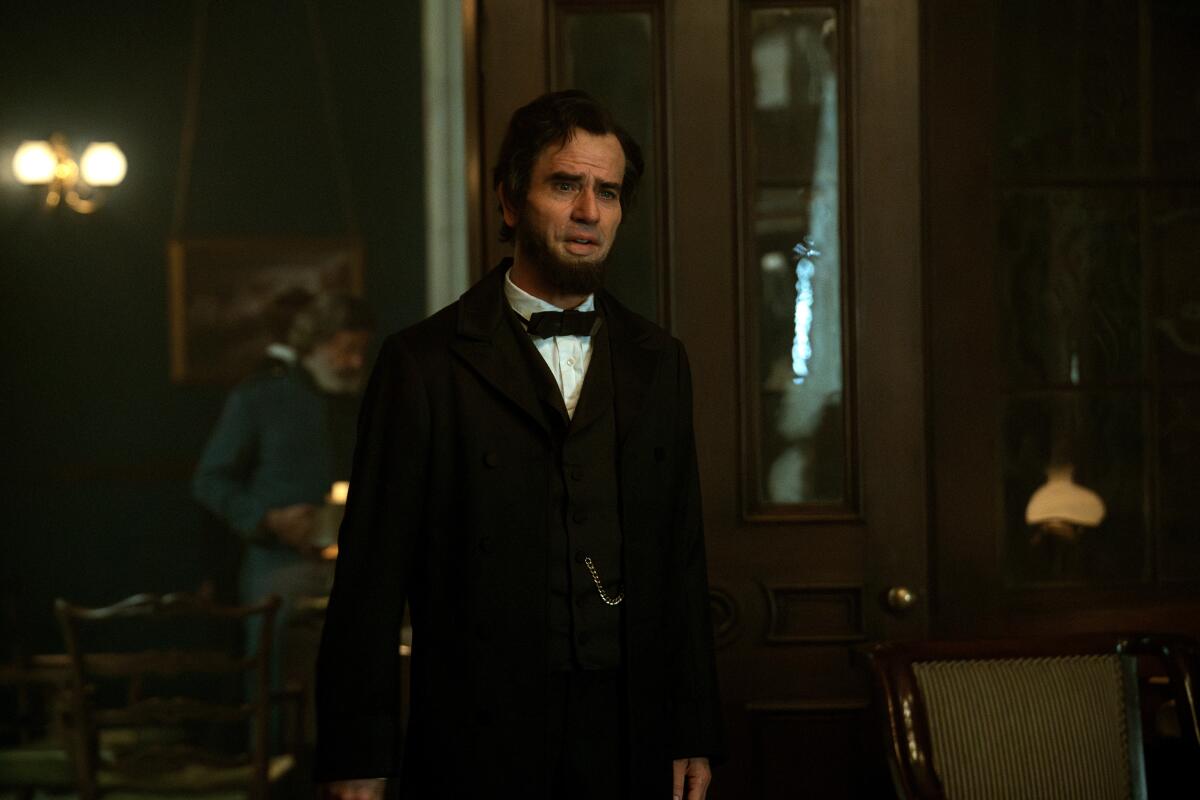 Hamish Linklater as Abraham Lincoln with a beard and wearing a black suit and bowtie.